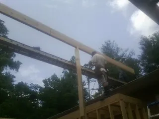Carpenter setting a ridge beam over a new addition frame — Ice Dam Removal by Roofing Brothers in Gambrills