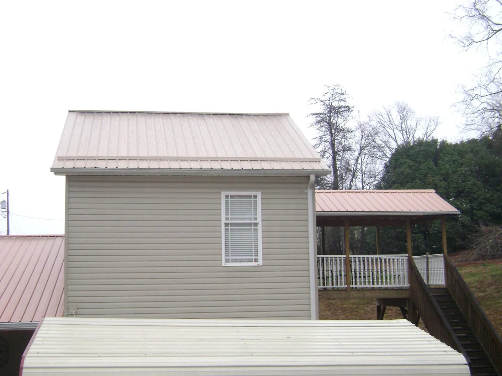 Tan metal roofs on a two story addition and attached porch, from a Roof Replacement job in Gambrills